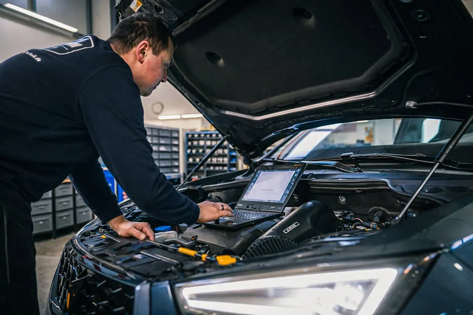 Techniker mit Laptop diagnostiziert Fahrzeug